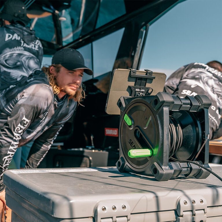 Person on a boat using the Seavu Explorer Adventure Kit reel and tablet to view live underwater footage from an action camera