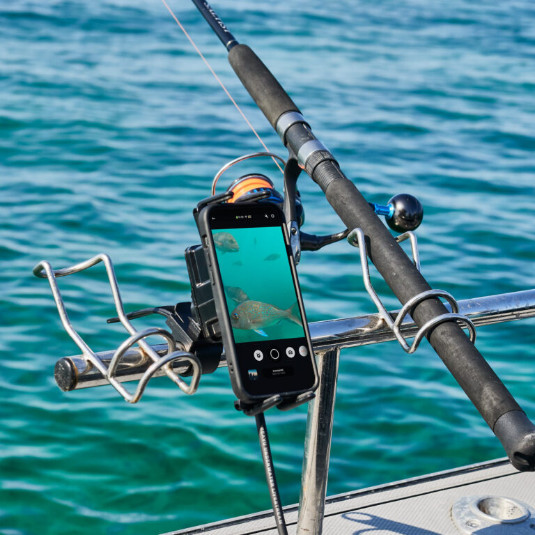 Phone connected to Seavu Seeker showing live underwater footage of snapper with fishing rod in background