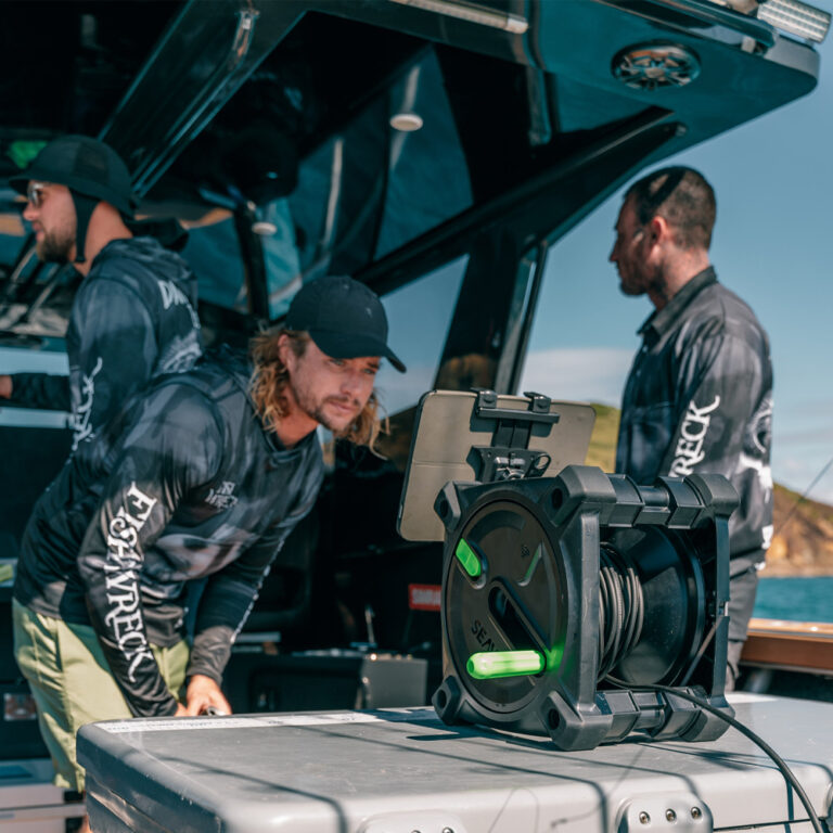 Recreational anglers watching live underwater fishing camera feed on a boat