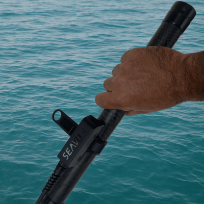 Hand holding Seavu extension pole with transmitter that sends Wi-Fi and Bluetooth signals to phone or tablet for live underwater streaming
