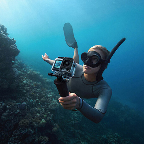 Woman underwater filming with the DJI Osmo Action 5 Pro, one of the best underwater cameras compatible with Seavu kits.