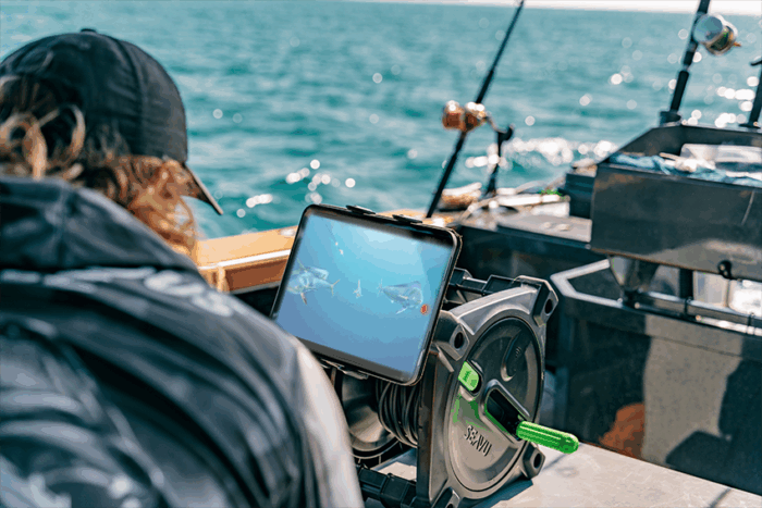 Person on a boat watching a live underwater feed of mahi mahi on a tablet mounted to the Seavu Explorer Reel