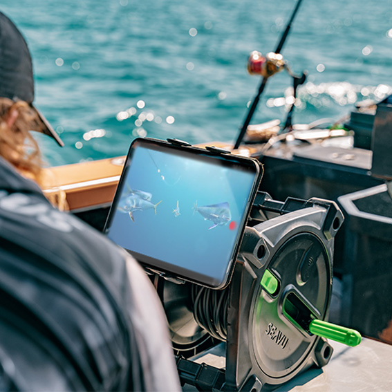 Person on a boat watching live underwater footage of Mahi Mahi on a tablet connected to a Seavu underwater camera system