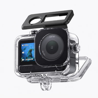 DJI Osmo Action 6 inside a clear waterproof housing with the back door swung open, black lens cover lifted above the camera, rear screen showing an underwater fish scene, and a two-prong mount underneath