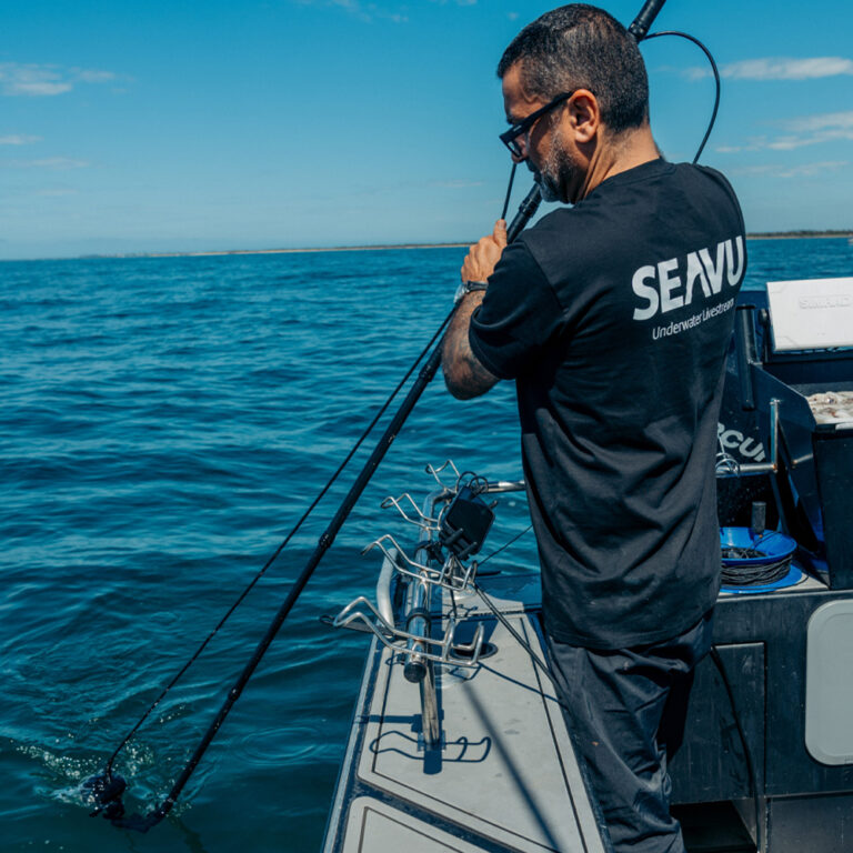 Person using a Seavu Seeker Marine Kit on a carbon fibre pole from a boat, with a phone showing live underwater view