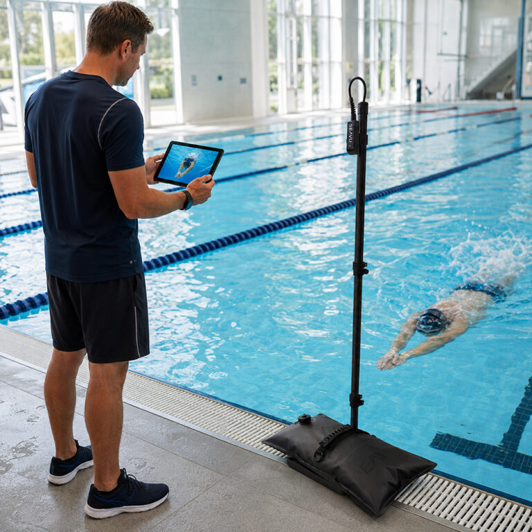 Coach using a tablet with the Seeker Pole Kit and Poolside Pole Base with weight bag for live underwater swim coaching
