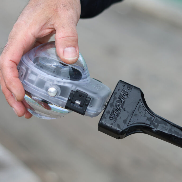 Hand attaching a DJI Osmo 360 in its Invisible Waterproof Case to the 1/4" screw mount of the Seavu Orbit 360